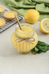 Homemade lemon curd in glass jar with fresh lemons
