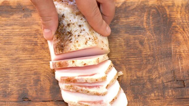 Slicing of salted pork fatback on cutting board, close-up. Ukrainian traditional food - salo