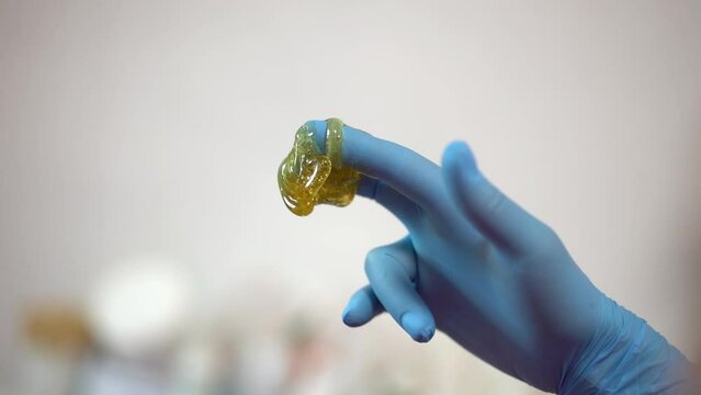 Sugar paste on a hand in blue glove. Poster, copy space. Sugaring salon