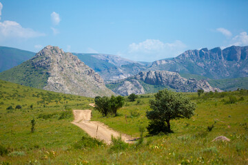 Beautiful highlands nature landscape in summer. Panoramic view of the mountains in the distance, blue clouds over the mountains. Long banner of mountain panorama.