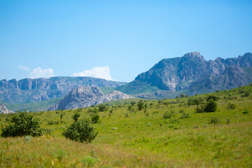 Beautiful highlands nature landscape in summer. Panoramic view of the mountains in the distance, blue clouds over the mountains. Long banner of mountain panorama.