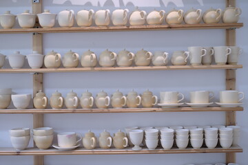 ceramic bowls and dishes on wooden shelves at pottery studio
