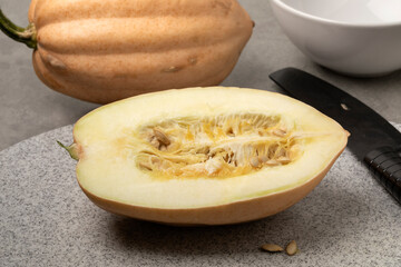 Whole and halved fresh Baked potato Acorn Squash on a cutting board close up