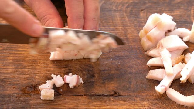 Slicing of salted pork fatback on cutting board, close-up. Ukrainian traditional food - salo