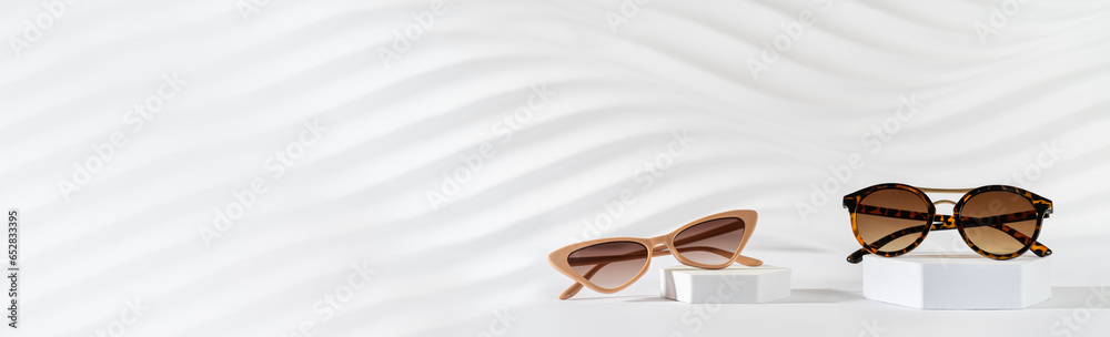 Wall mural Sunglasses sale banner. Summer sale-out offer. Trendy sunglasses in plastic frame on podiums on a white background. Copy space. Optic store discount, promotion banner, web line. Minimal still life