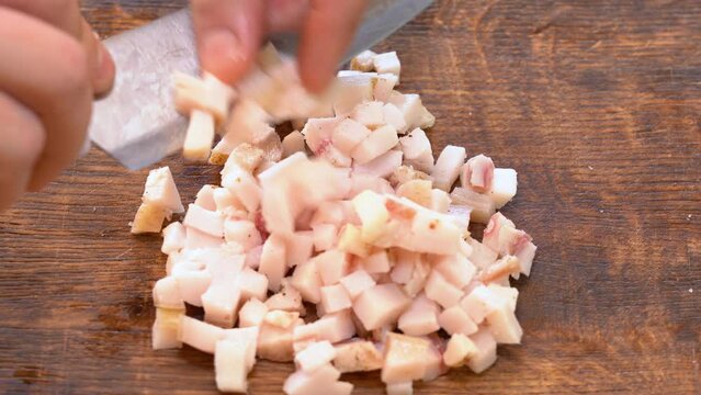 Slicing of salted pork fatback on cutting board, close-up. Ukrainian traditional food - salo