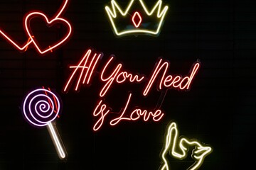 Bright neon sign with the phrase "All You Need Is Love" illuminated against a dark background