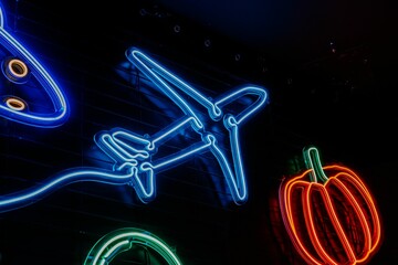 Vibrant, colorful wall display with neon lights, signs of an aircraft and a pepper