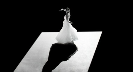 Woman wearing a white bridal gown dancing illuminated in a dark atmosphere