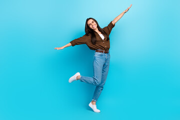 Full size body cadre of girl young flying arms have fun positive playing lightness freedom stylish outfit isolated on blue color background