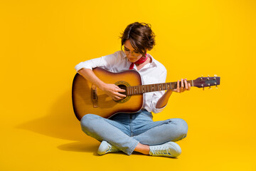Photo of adorable lovely girl wear stylish outfit sitting floor learning play guitar isolated on yellow color background - obrazy, fototapety, plakaty