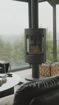 Sal&oacute;n acogedor con chimenea encendida, complementado por un majestuoso ventanal que ofrece vistas panor&aacute;micas a un bosque sereno. Ideal para escenas hogare&ntilde;as y naturales