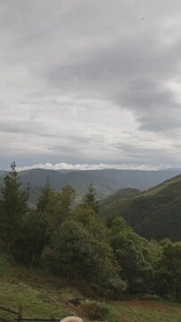 Vista majestuosa desde un ventanal hacia una monta&ntilde;a con &aacute;rboles frondosos, iluminada por un sol resplandeciente que se asoma entre nubes. Un momento de serenidad y conexi&oacute;n con la naturaleza