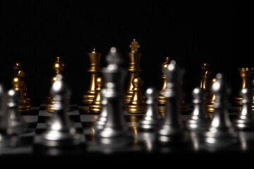 A golden chess army prepares to play in a dark room.