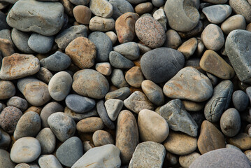 Rounded stones on a beach in Maine's Arcadia National Park with tones of gray, gold, rust, white.