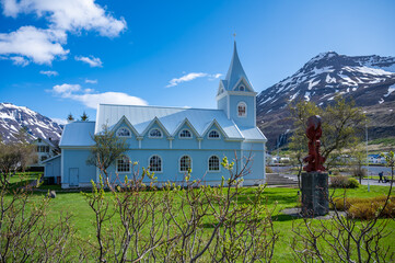 Blue wooden Church at Seydisfjordur, Iceland, view from the side with snow mountains in the background