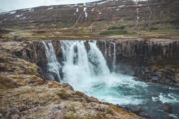 Beautiful Waterfall at Seydisfjordur, Iceland with snow mountains in the background