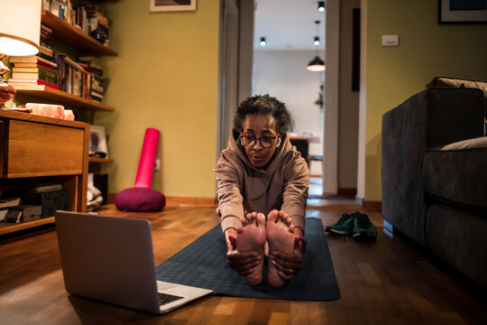 Senior African American woman mimicking a workout video on her laptop at home