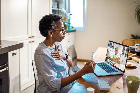 Senior African American woman consulting her doctor via a video call about her medication in the kitchen at home