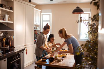 Young and diverse group of friends preparing organic healthy shakes in the kitchen at home