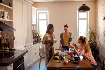 Young and diverse group of friends having coffee while getting ready to prepare organic healthy shakes in the kitchen at home