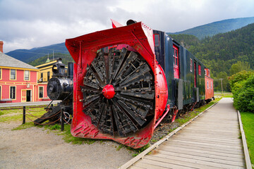 Retired rotary snow plow at the front of an old White Pass & Yukon Railroad train in the city center of Skagway, Alaska - Old snow blower train in the Klondike Gold Rush National Historic Park - obrazy, fototapety, plakaty