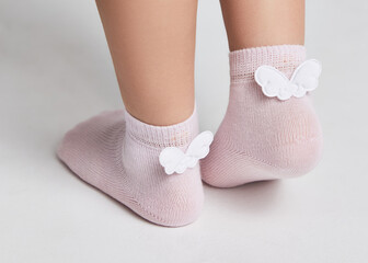  Children wearing pair of socks. Top view to kids foots in mismatched socks sitting on white background. Odd Socks day. Beautiful baby feet in cute socks. Gray background. Close-up.
