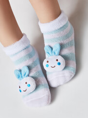  Children wearing pair of socks. Top view to kids foots in mismatched socks sitting on white background. Odd Socks day. Beautiful baby feet in cute socks. Gray background. Close-up.