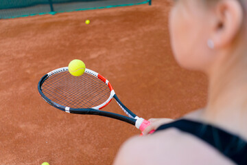 young girl beginner tennis player hitting the ball with a racket on the court practicing and learning to hit and serve sport hobby close-up