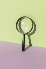 A classic magnifying glass on a purple-green background.