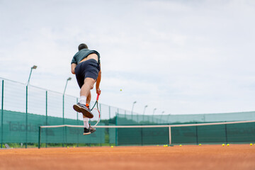 young professional player coach on outdoor tennis court practices strokes with racket and tennis ball