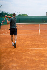 young professional player coach on outdoor tennis court practices strokes with racket and tennis ball