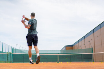 Obraz premium young professional player coach on outdoor tennis court practices strokes with racket and tennis ball