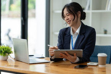 Smiling Asian business woman Delight in the achievements by using the tablet to work with plans, ideas, ideas to present. financial report business plan investment new age concept online