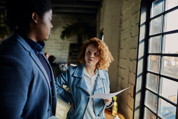 Two young and diverse designers going over paperwork together in a startup company office