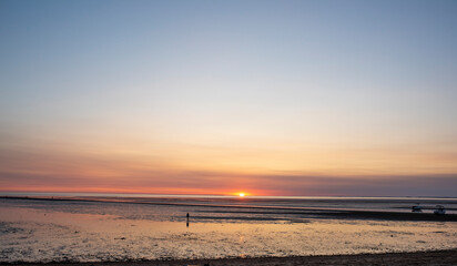 A solitary person walks out during low tide