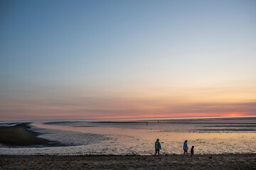 A family plays around on low tide during a Cape cod summer sunset