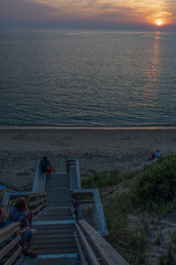 People line the stairs to capture and enjoy the fleeing last rays of a summet sunet on Cape Cod