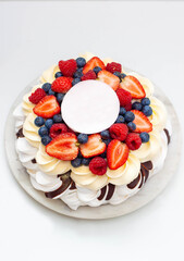 Pavlova cake with whipped cream cheese, chocolate sauce and fresh berries on marble grey background
