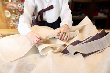 한국 전통복장인 한복 명인이 한복 제작을 위해 바느질을 하고있다 