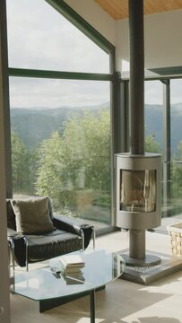 Sal&oacute;n monta&ntilde;&eacute;s con chimenea encendida y ventanal panor&aacute;mico, mostrando laderas frondosas al amanecer