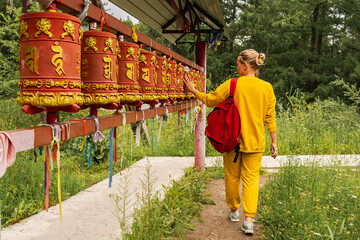 Person pilgrim woman touching turning spinning Buddhist prayer wheel at Buddhist monastery. Prayer...