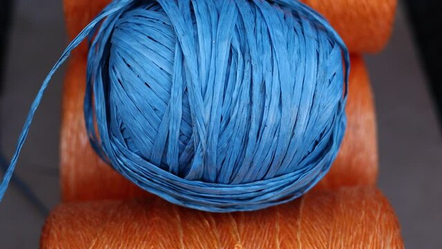 rolls of natural hemp wire for parcel twine, string, packing or diy.fencing strand,polypropylene orange, blue twine.spools in plastic bag,woman hand,market store sale concept.thick rope texture