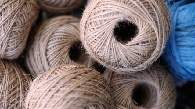 rolls of natural hemp wire for parcel twine, string, packing or diy.fencing strand,polypropylene orange, blue twine.spools in plastic bag,woman hand,market store sale concept.thick rope texture