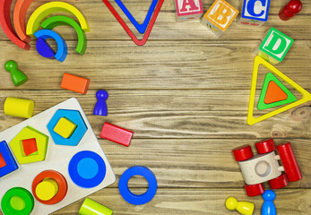 Wooden kids toys on wood background. Educational toys blocks, pyramid. Toys for kindergarten, preschool or daycare. Copy space for text. Top view