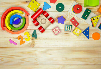 Wooden kids toys on wood background. Educational toys blocks, pyramid. Toys for kindergarten, preschool or daycare. Copy space for text. Top view