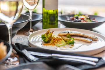 Dorado or sea bass fillet in cream sauce with broccoli on a white plate isolated