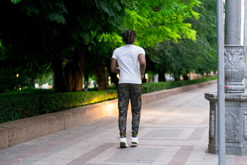 black person doing sport activity outdoors, jogging in the city in the evening