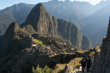 Panorama of Machupicchu with view of the mountains and archeological site, along with a stone staircase to the ruins with silhouettes of people descending it, in Peru, Sacred Valley. 