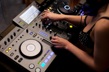 Female disc jockey hands mixing tracks on professional sound mixer, playing music during night at...